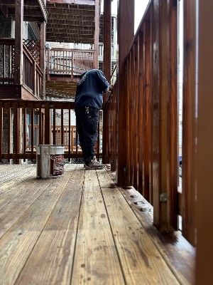 Crew member staining a porch railing