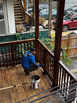 Crew member staining a back-porch railing