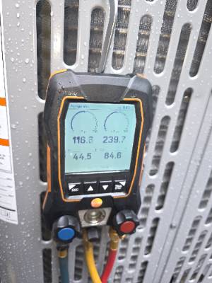 Digital manifold gauges reading refrigerant pressures during an AC service call