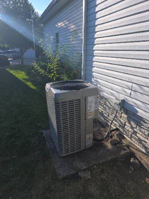 Air conditioner condenser on a slab beside a home in evening light