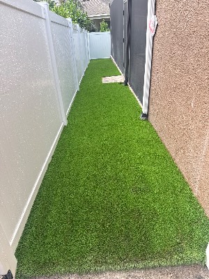 Side-yard artificial grass cut around a paver landing