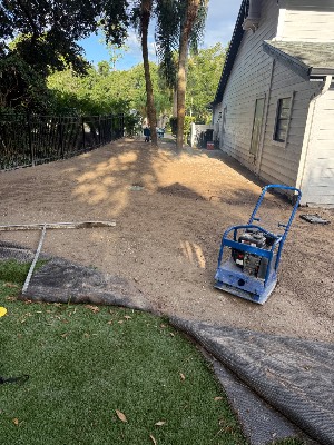 Graded soil and a plate compactor after the old lawn was removed