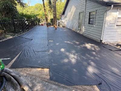 Weed barrier fabric laid over the compacted base before the turf goes down