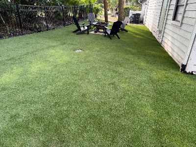 Finished artificial grass backyard with a fire pit and chairs