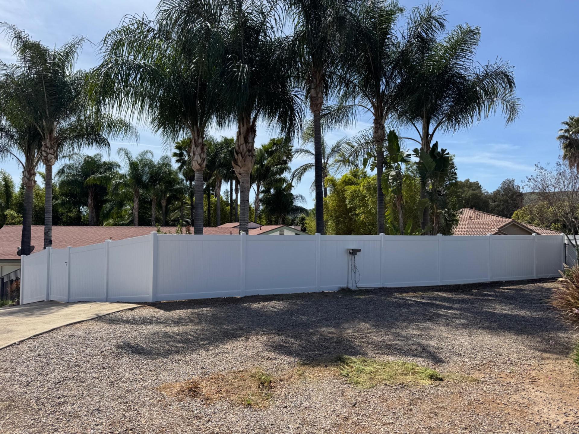 White vinyl privacy fence installed by Cornerstone Fence along a palm-lined property in San Diego County