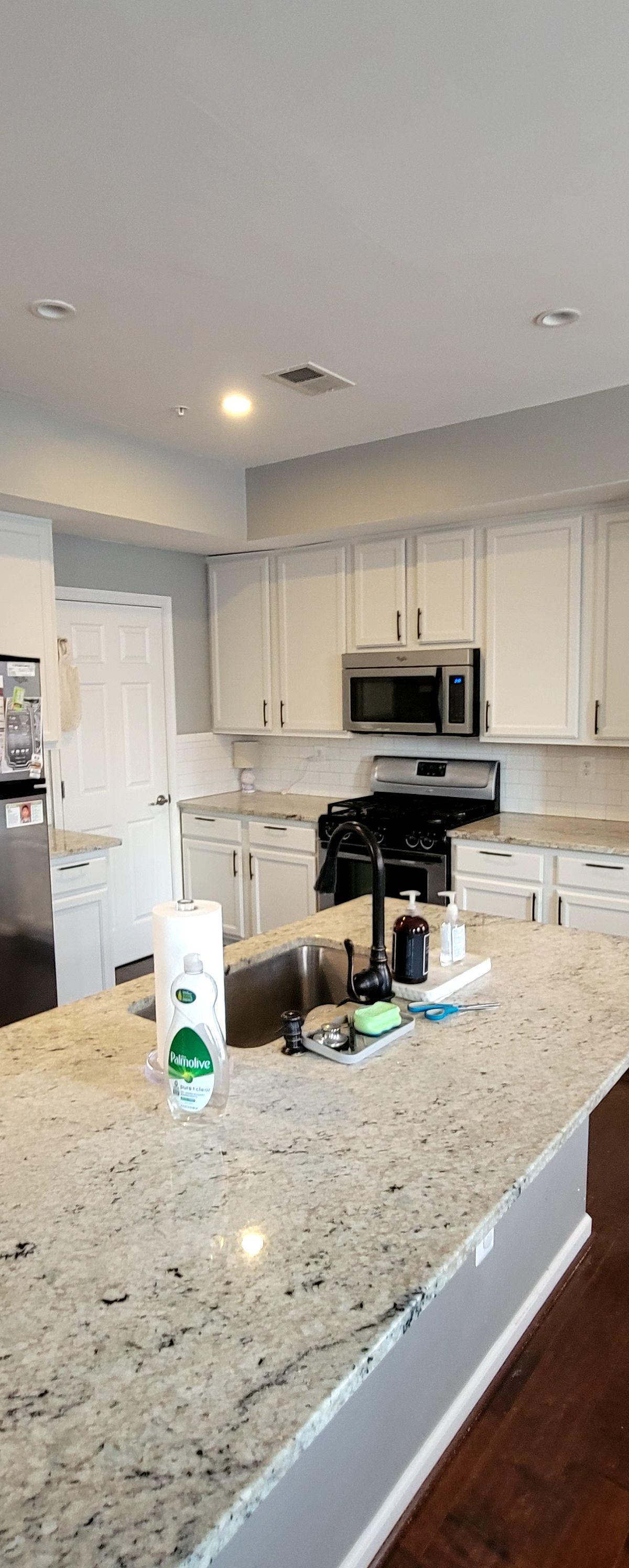 Remodeled kitchen with granite island and white cabinets by 4 Way Construction