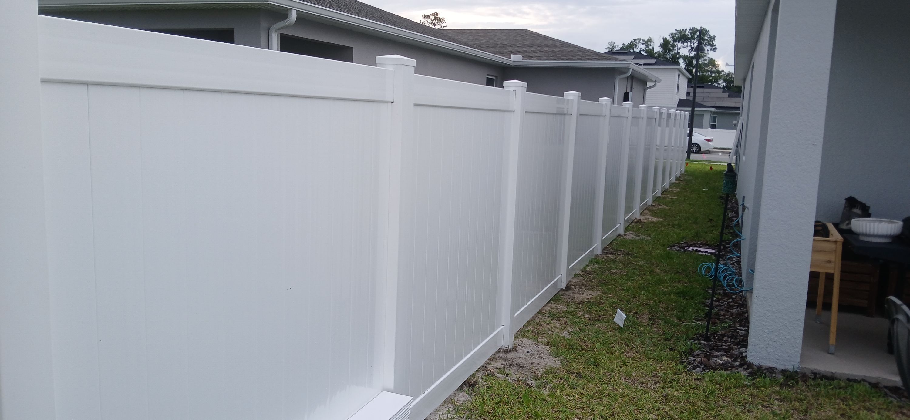 A white vinyl privacy fence running the side of an Orlando house over mown grass