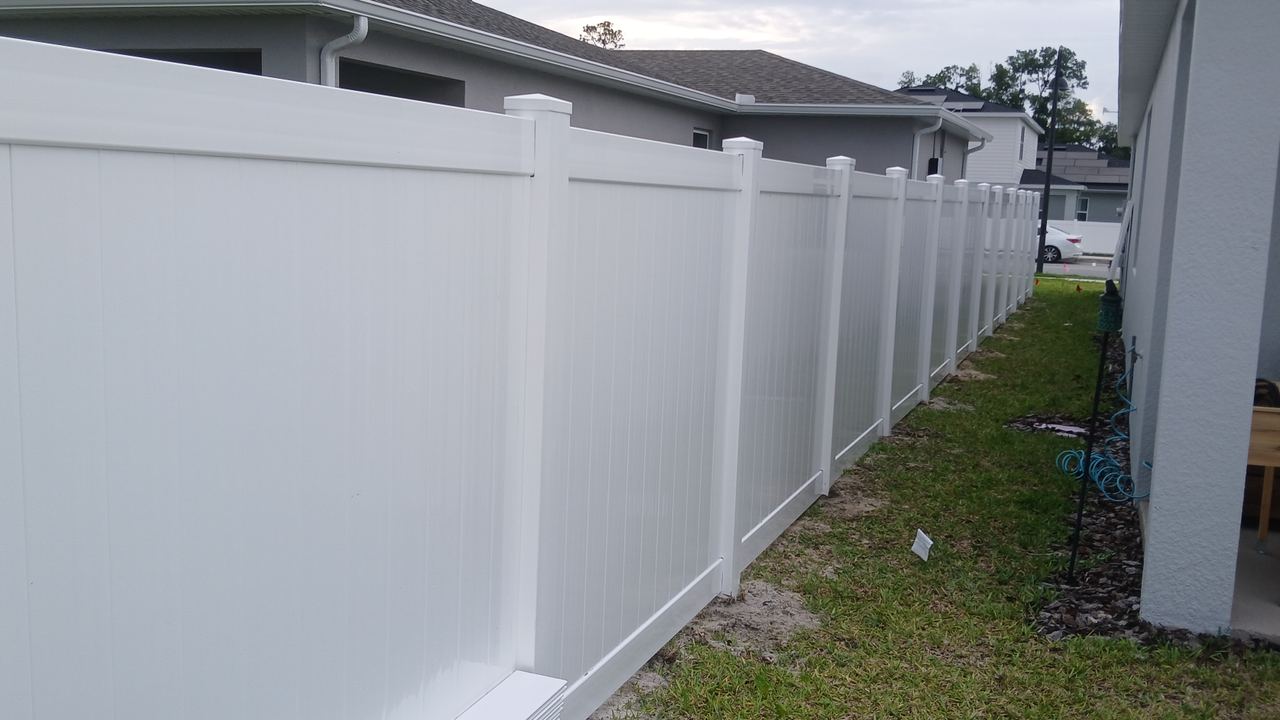 A white vinyl privacy fence running the side of an Orlando house over mown grass