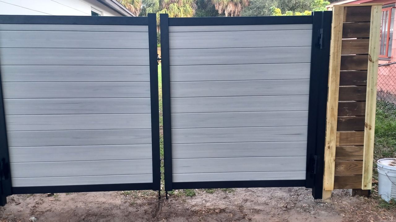 A double drive gate in grey composite board on a black steel frame, hung square between its posts