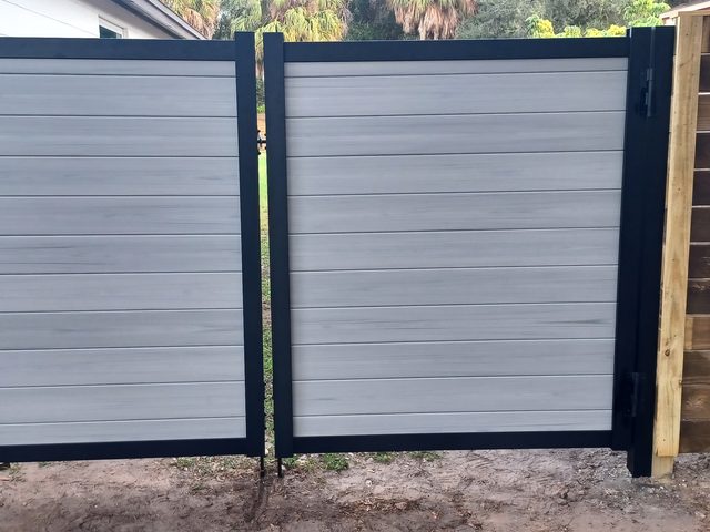 A double drive gate in grey composite board on a black steel frame, hung square between its posts