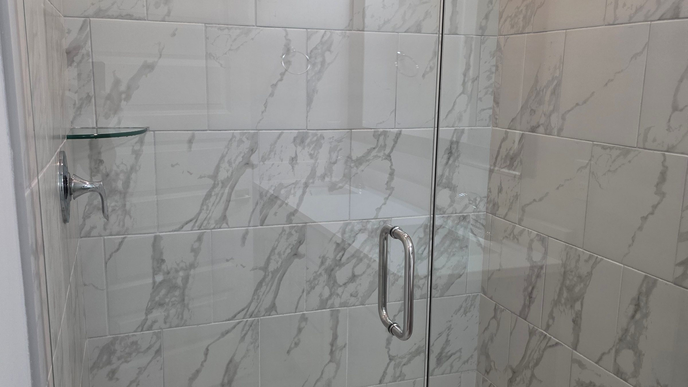 Scrubbed marble tile shower with streak-free glass cleaned by Sandra House Cleaning Service in Huntsville, AL
