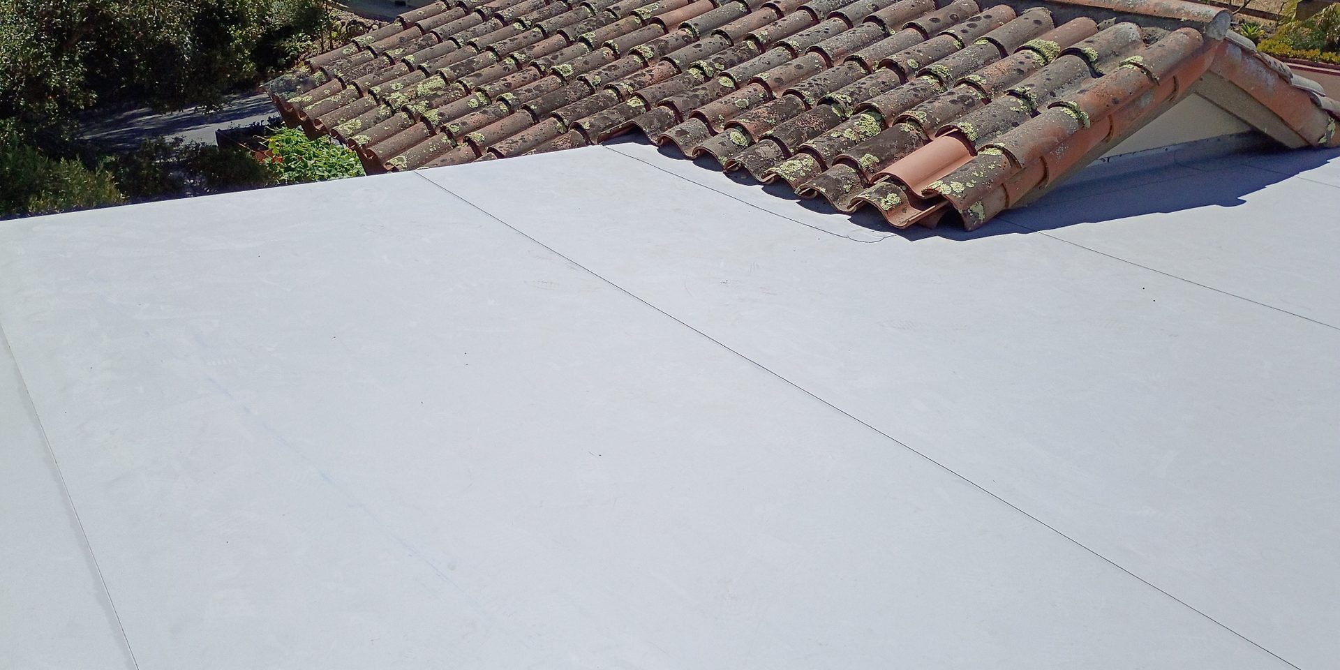 Alex Roofing single-ply flat roof meeting an existing tile roof
