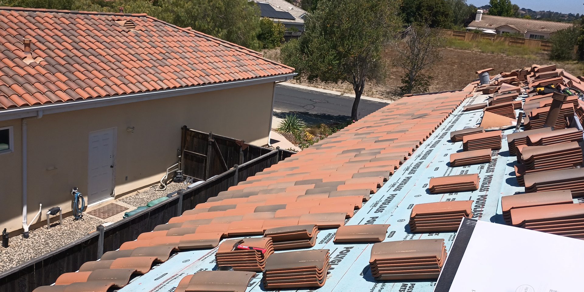 Roofing materials staged across new underlayment on an Alex Roofing job site