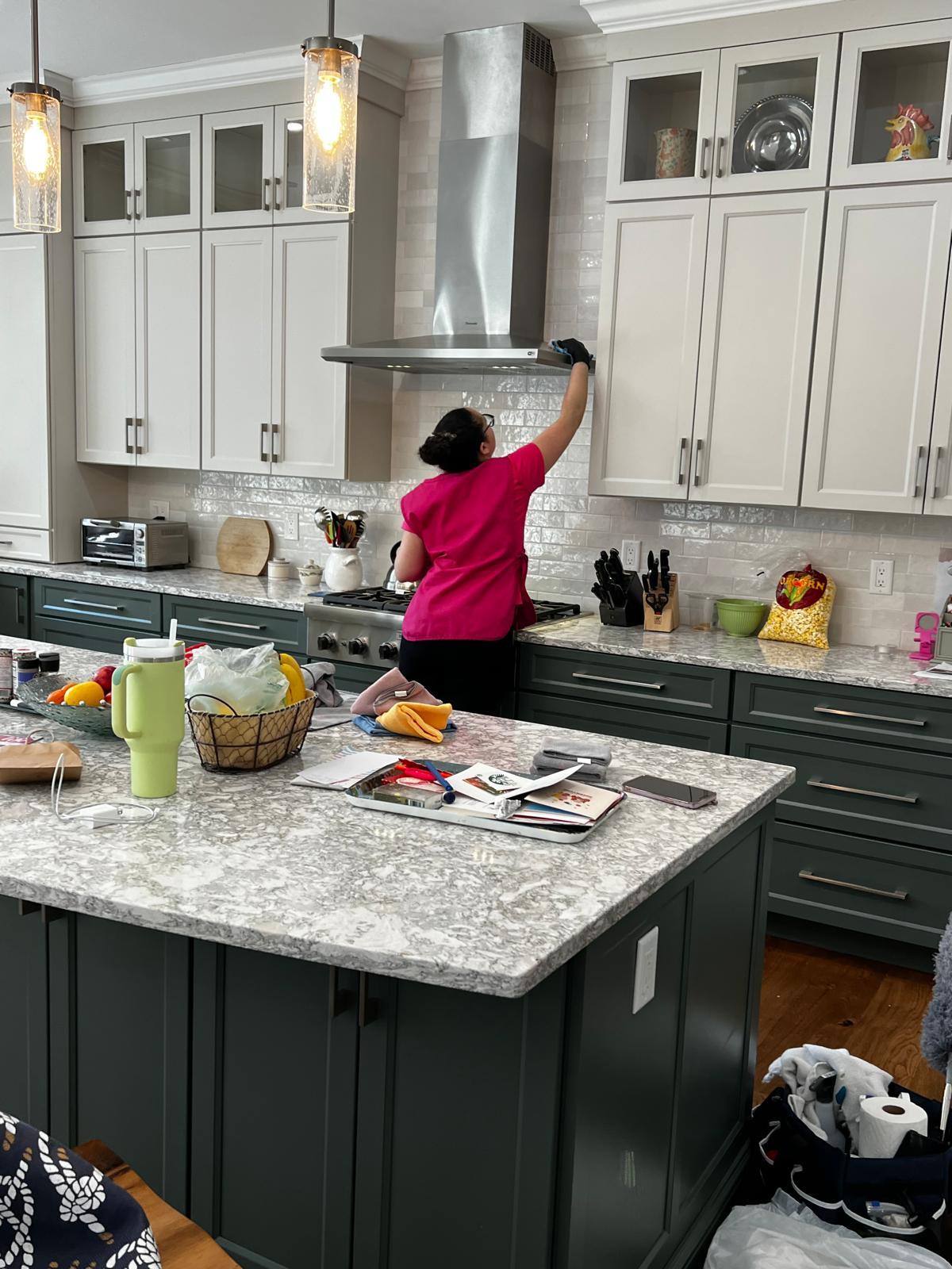 América Braga Cleaning team member wiping down white kitchen cabinets