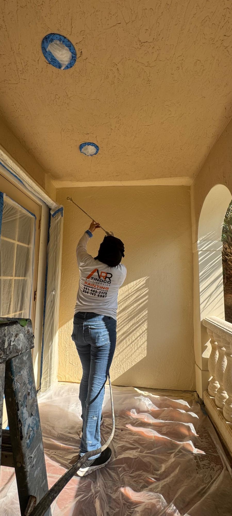 ARR Tinoco Multiservice painter working from a ladder on an exterior entryway ceiling