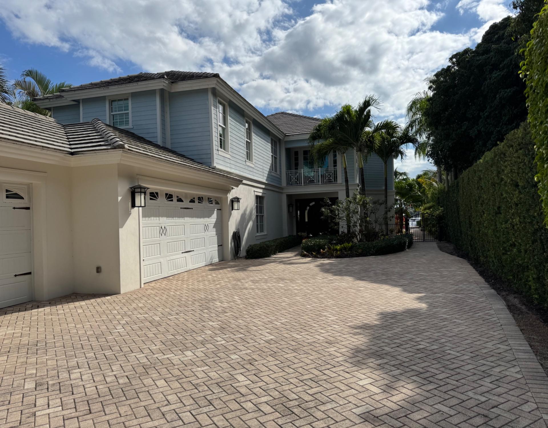 Repainted two-story home with a paver driveway in Palm Beach County, finished by ARR Tinoco Multiservice