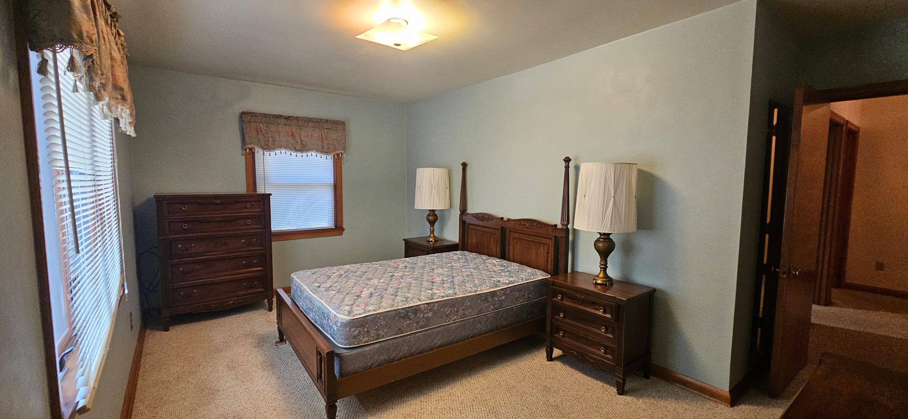The same furnished bedroom with soft sage green walls, bed, lamps and dresser, finished