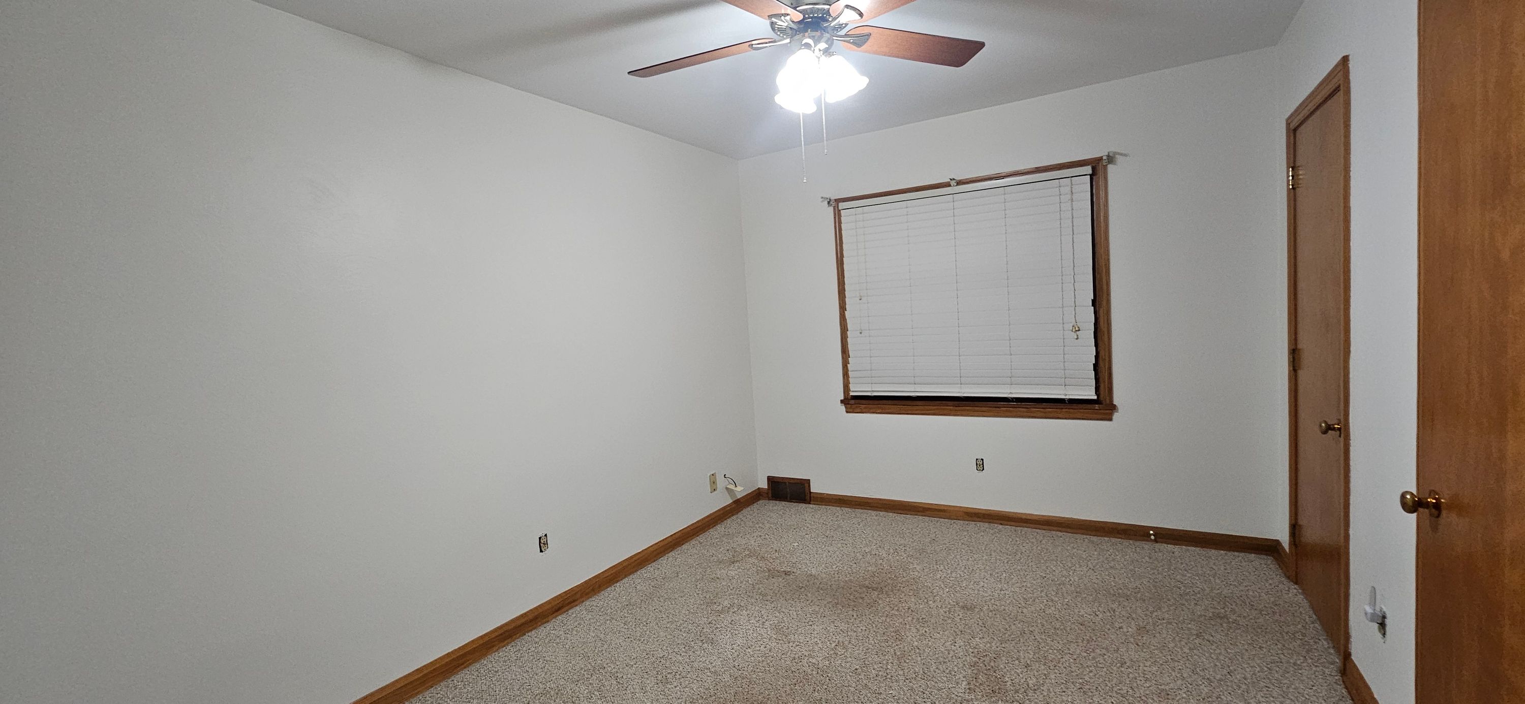 The same bedroom finished in clean white with ceiling fan, blinds and wood window trim