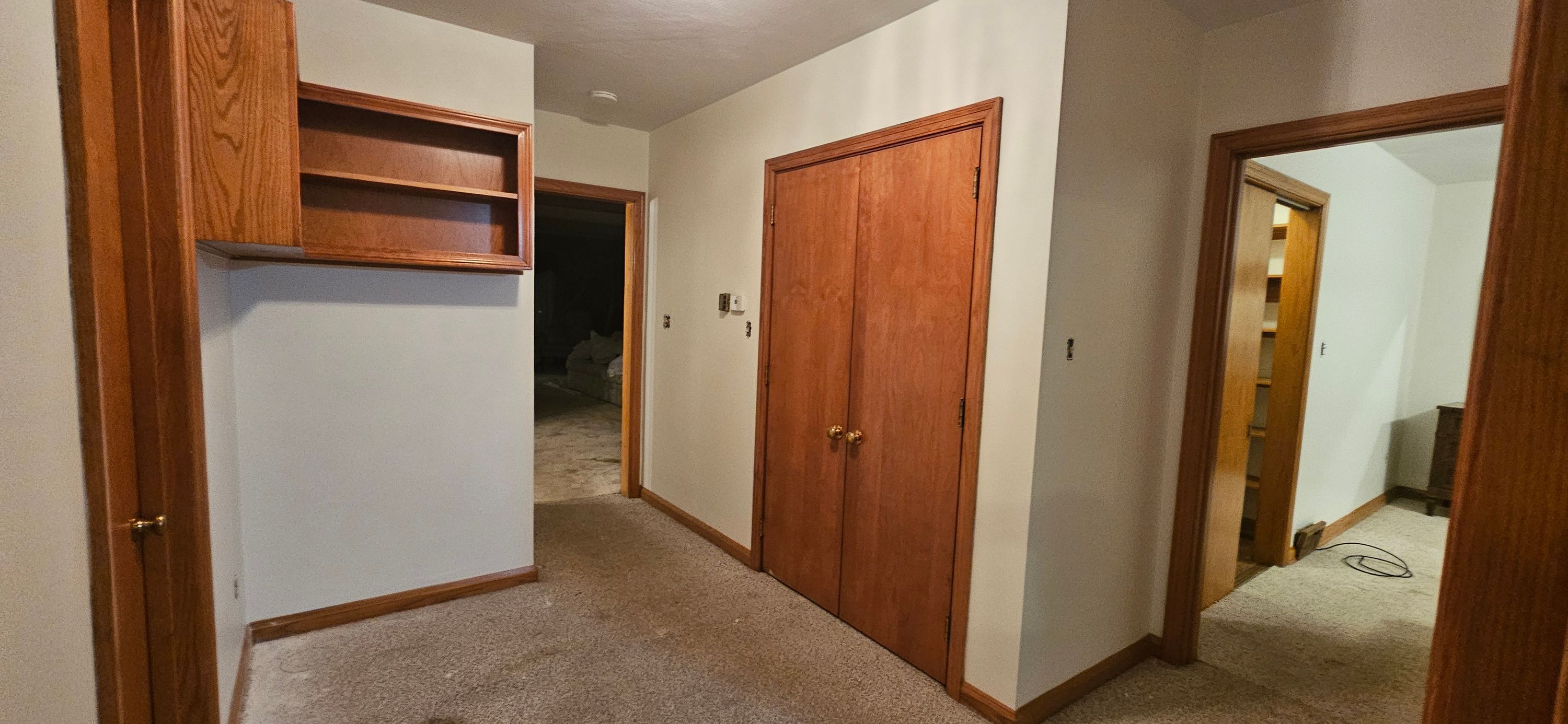 Upstairs hallway landing painted white around oak bifold closet doors and built-in shelving