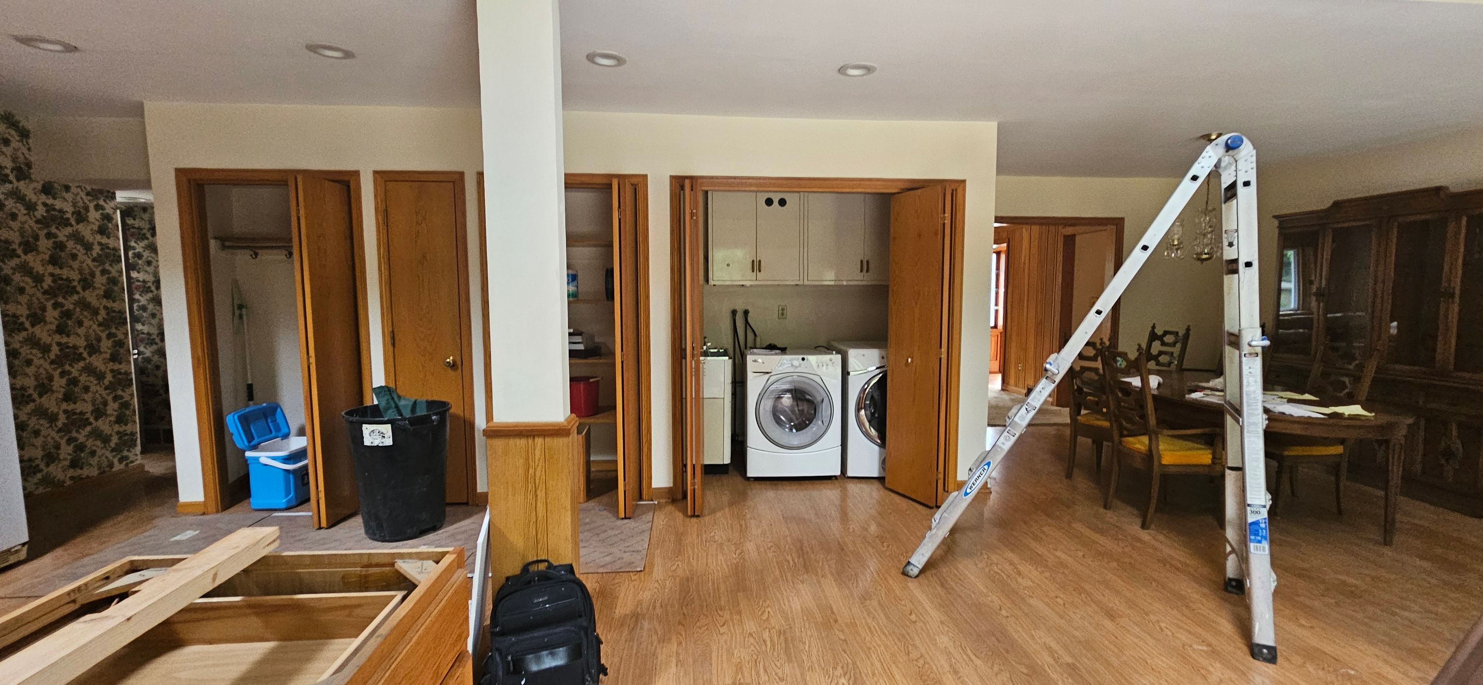 Laundry and closet hallway before painting, ladder set up against beige walls with oak doors