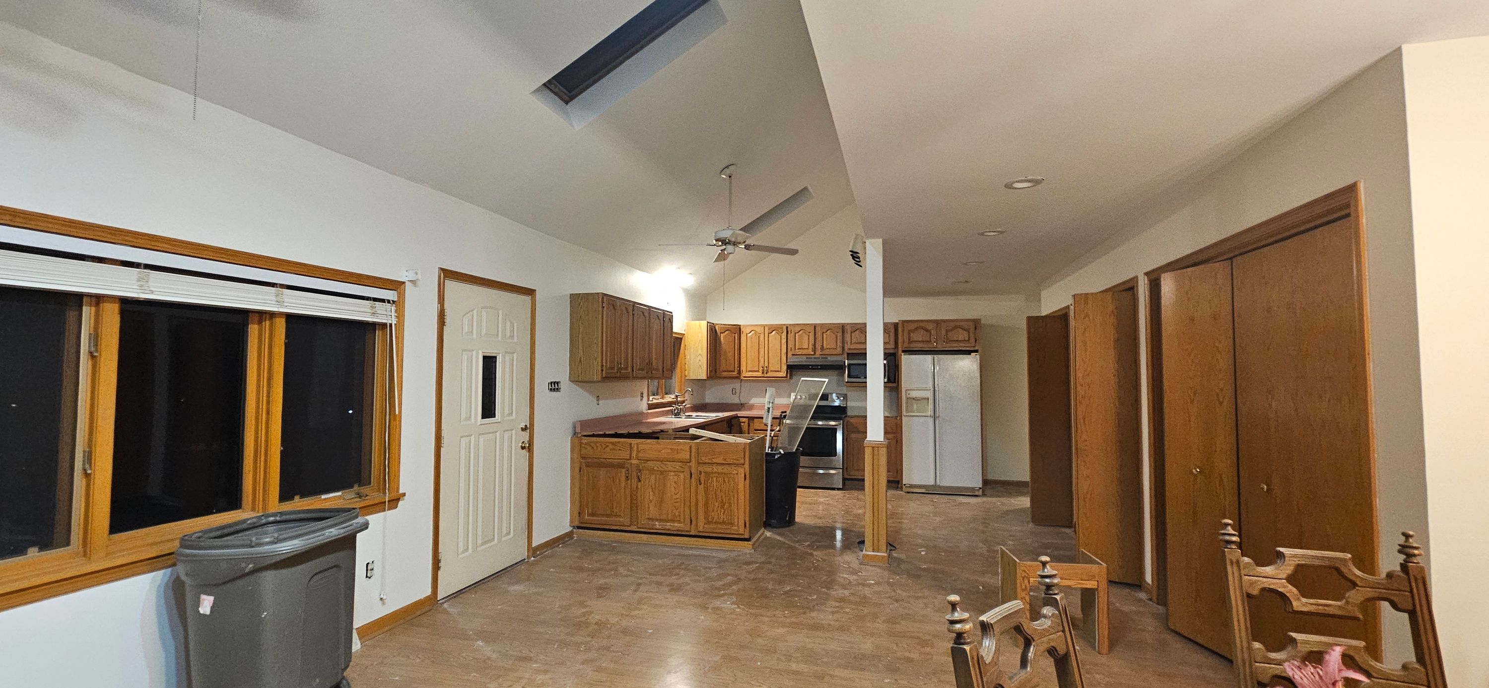 Vaulted kitchen and living space finished in white with oak trim and a skylight overhead