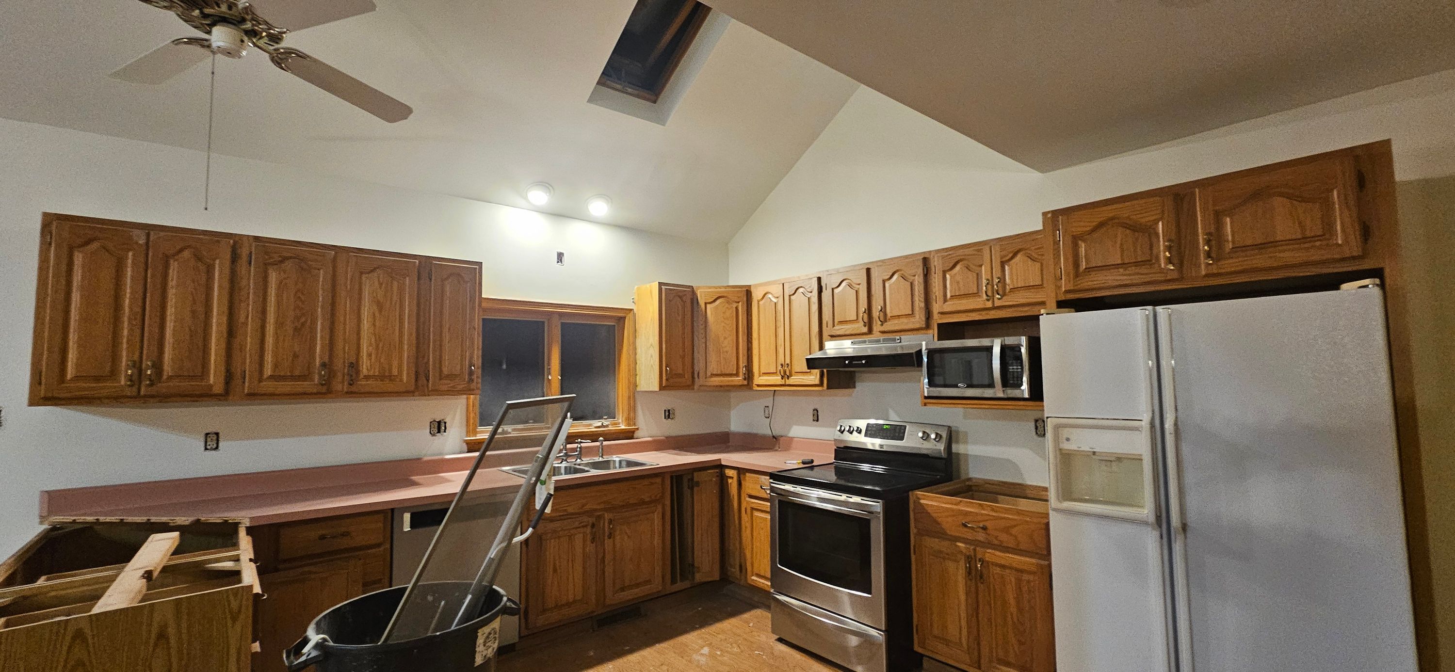 The same kitchen with walls repainted white, countertops covered and cabinet doors removed