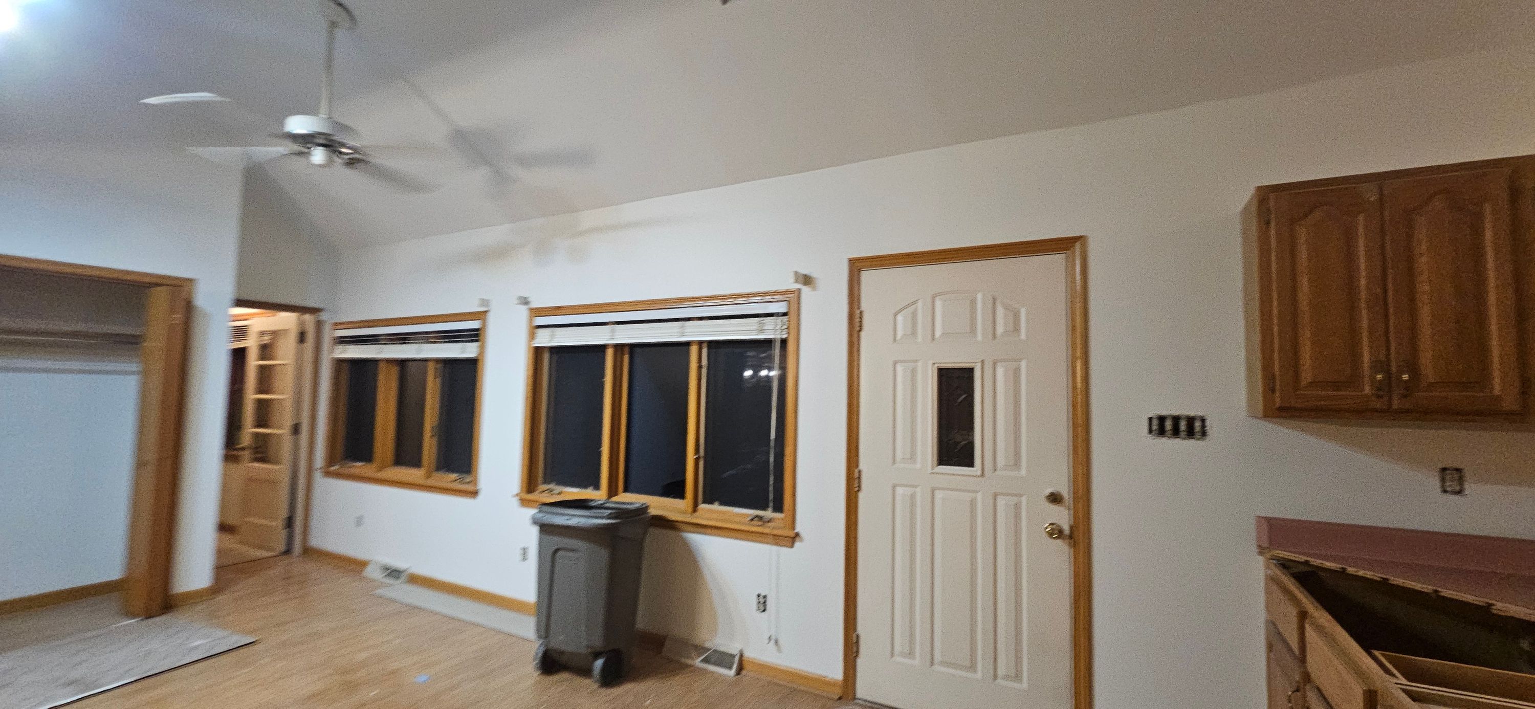 Kitchen dinette with newly painted white walls, oak trim, ceiling fan and vaulted ceiling
