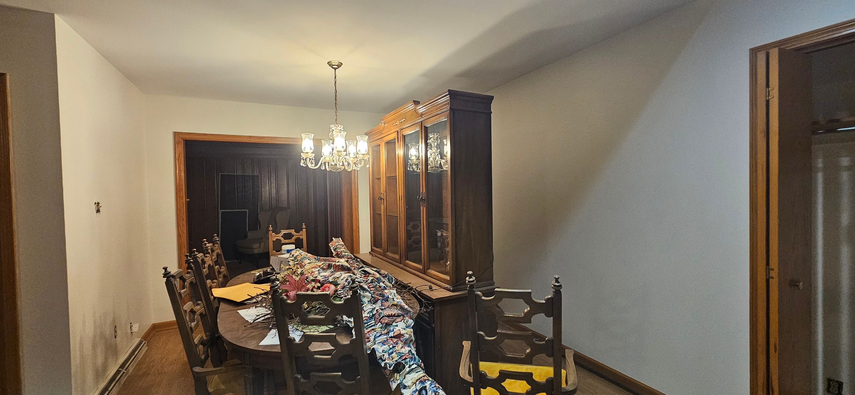 Dining room with pale repainted walls and furniture covered in plastic sheeting during the job