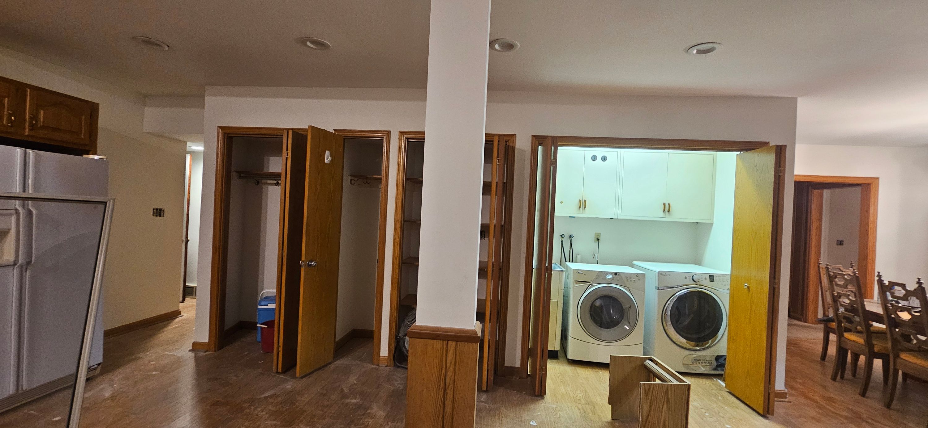 Basement laundry and closet area with white walls painted around oak doors, washer and dryer