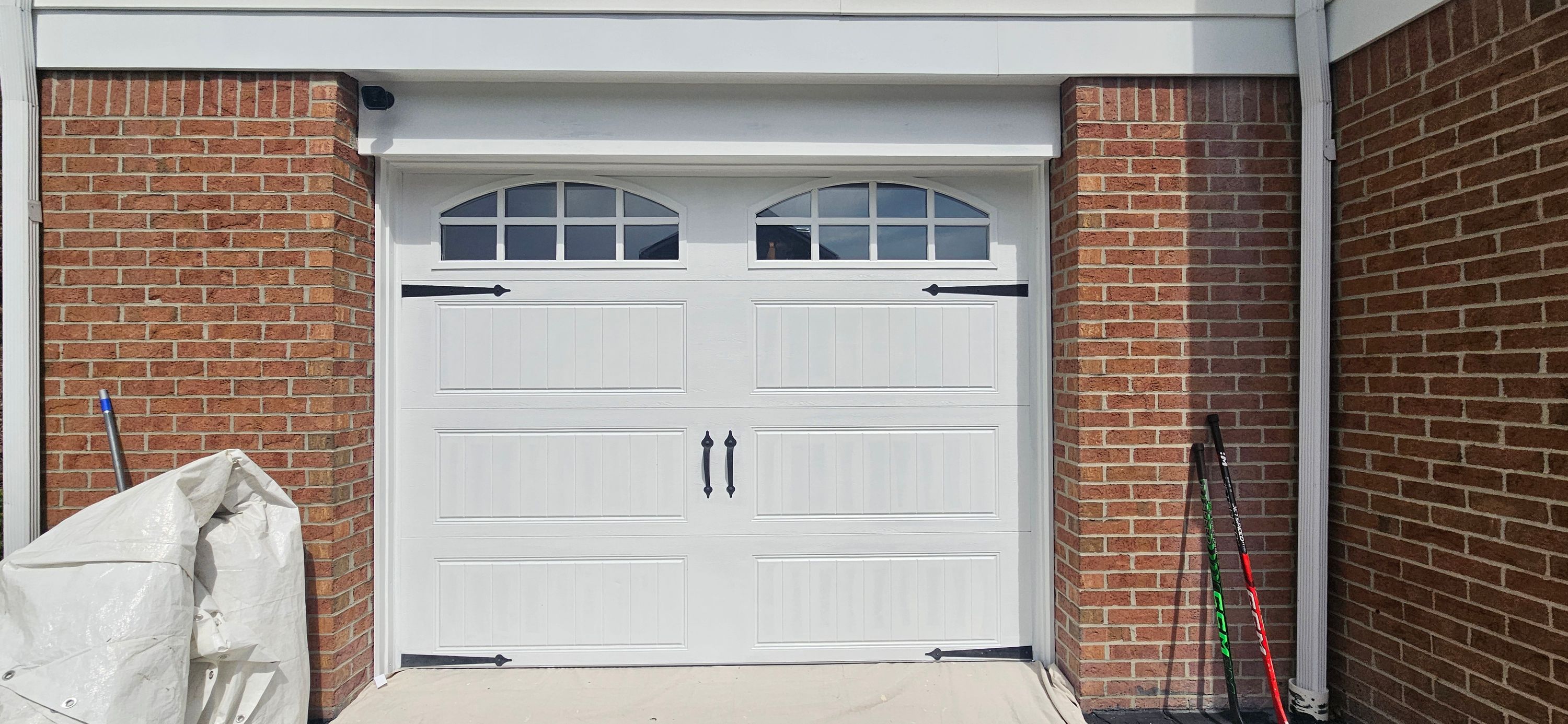 White garage door and surrounding trim finished between red brick columns