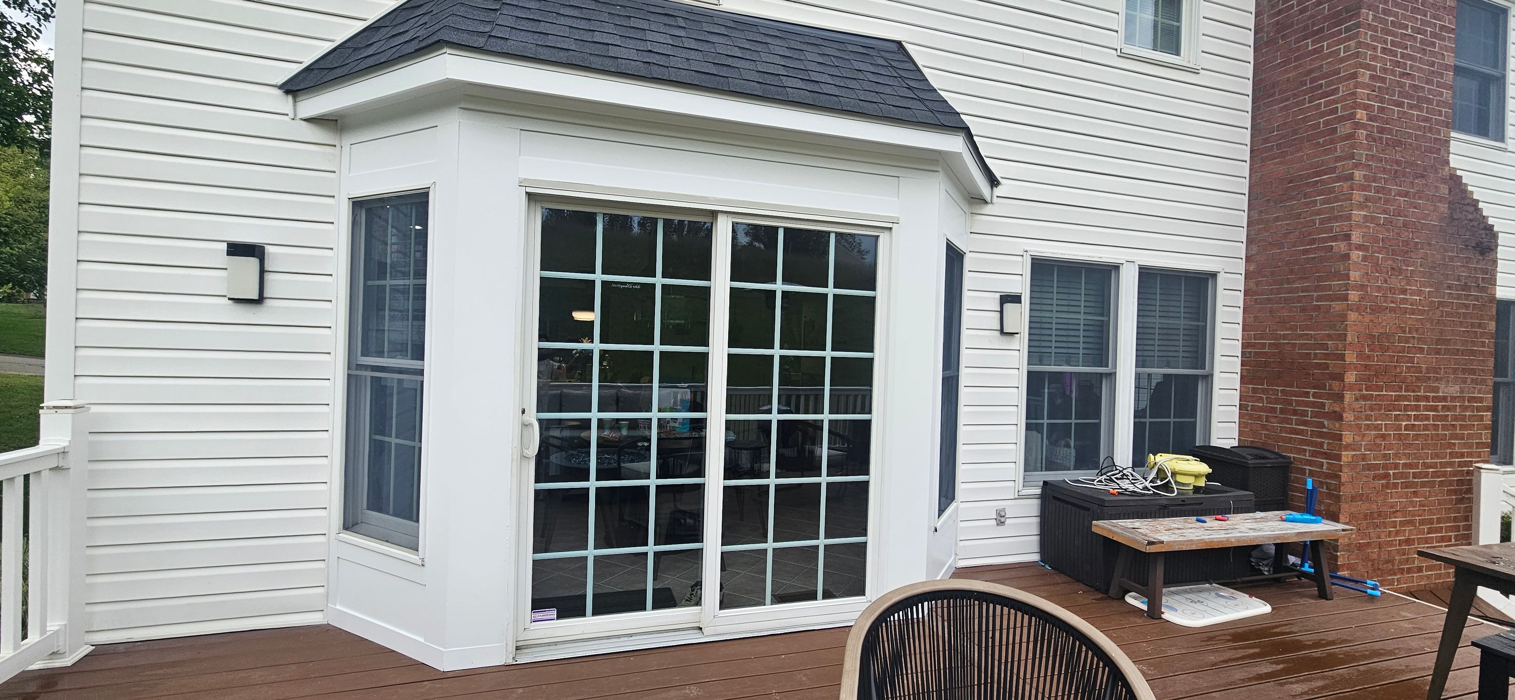 White siding and window trim on a house rear elevation with sliding doors, finished exterior