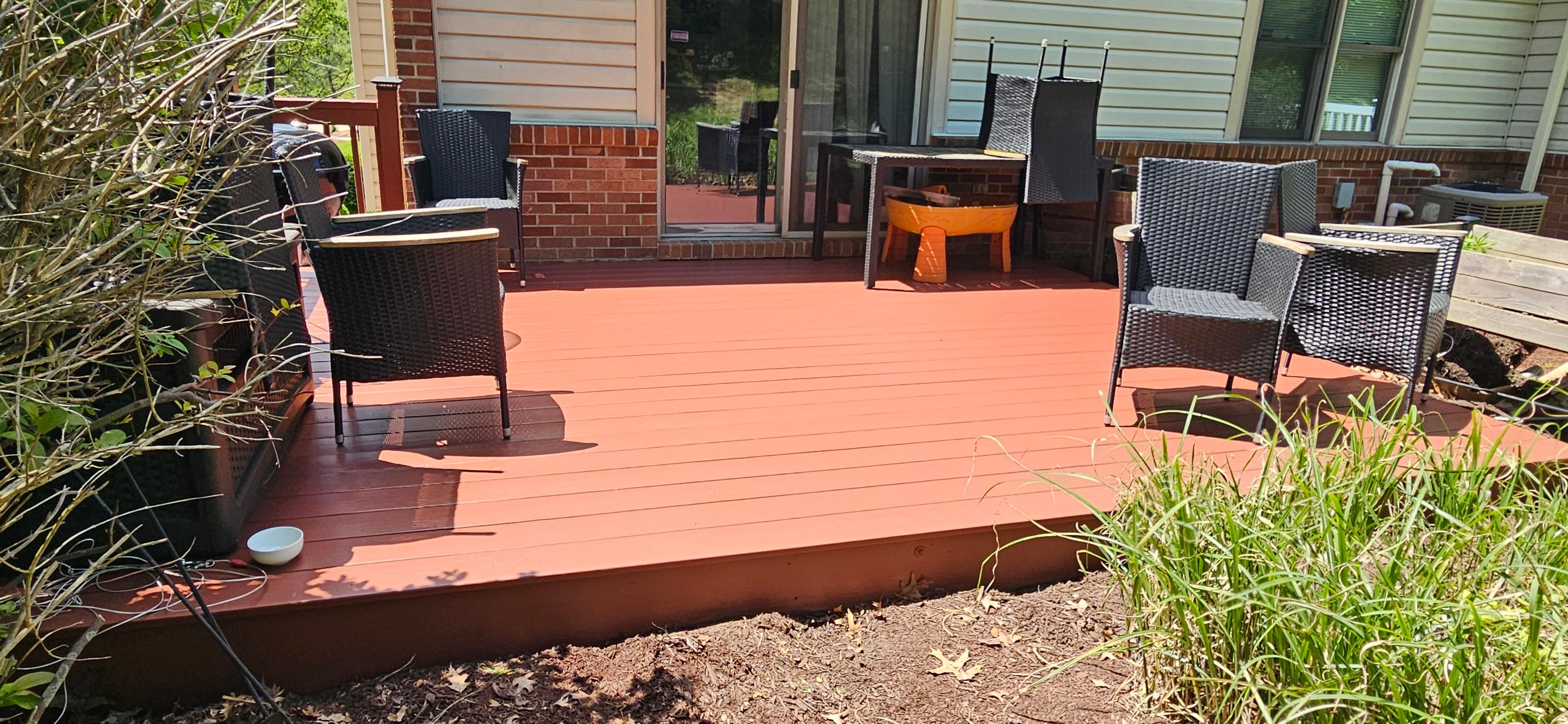 Backyard deck boards freshly stained terracotta red with patio furniture set back on top