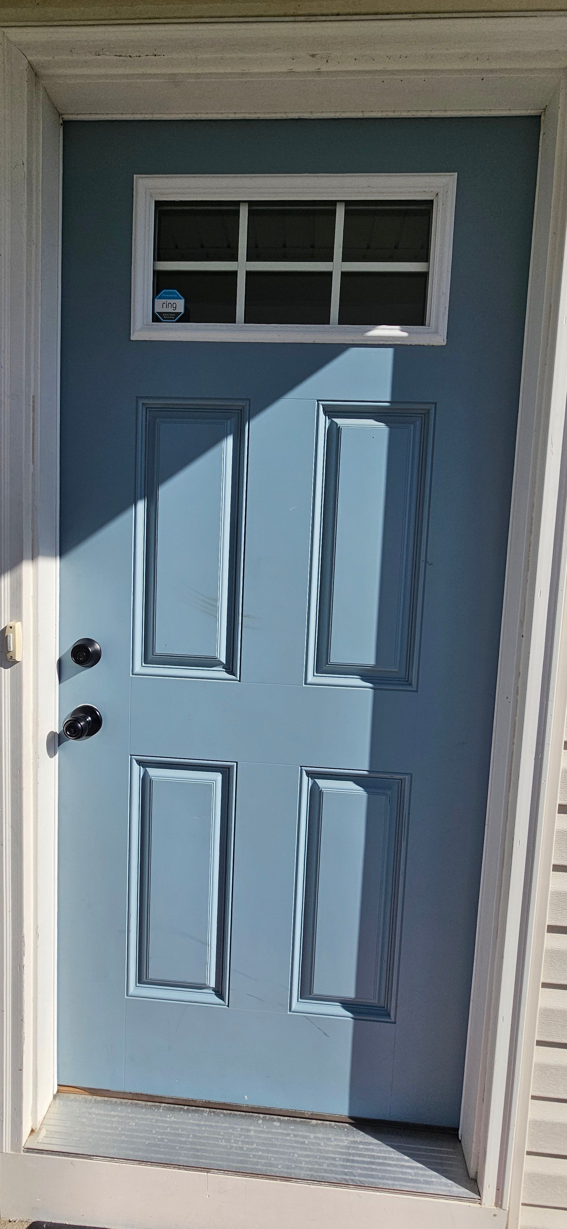 Exterior side of a steel entry door painted slate blue with white trim, finished