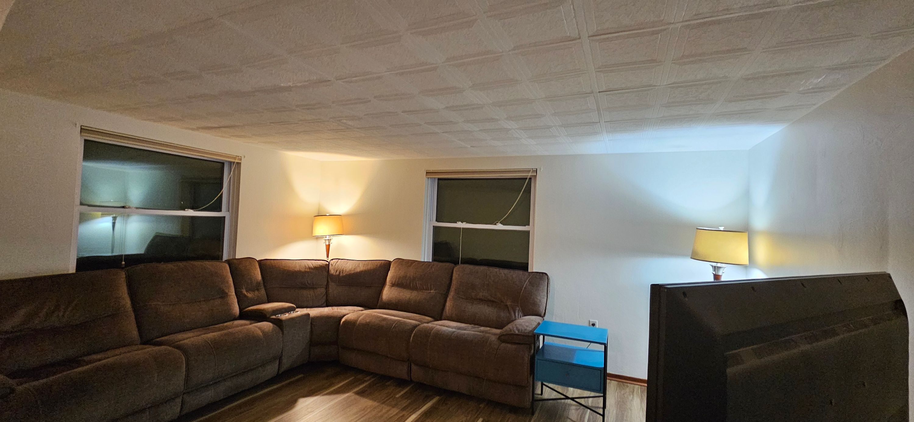 Living room with freshly painted off-white walls and textured ceiling above a brown sectional sofa