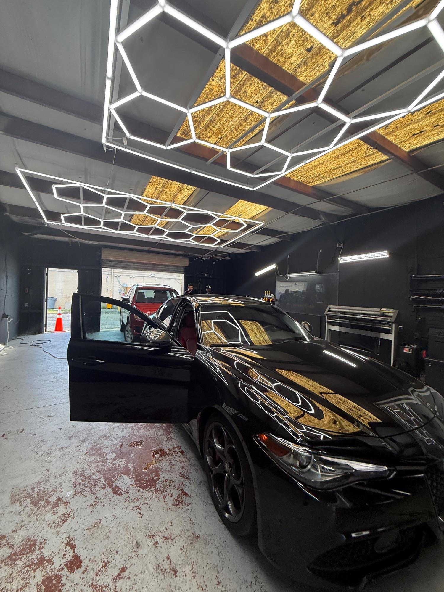 Black sports car with freshly tinted windows inside the Bris Window Tint install bay