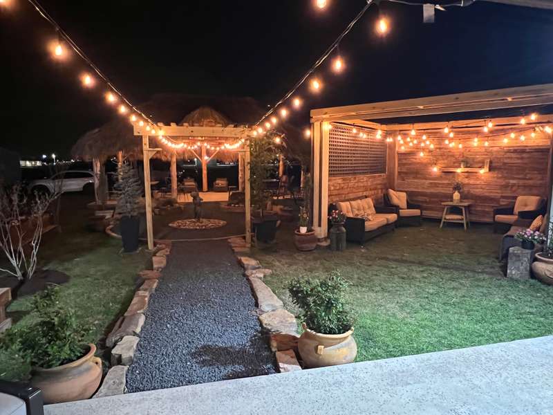 Landscaped courtyard with stone walkway and string lighting completed by Castle Lawncare & Landscaping LLC in Sanger, Texas