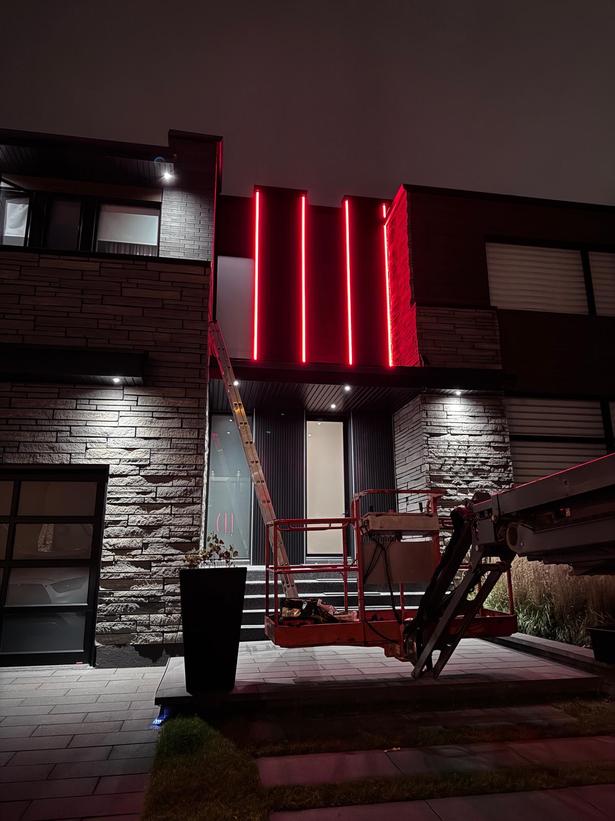Facade lighting installation on a modern home, with a lift on site