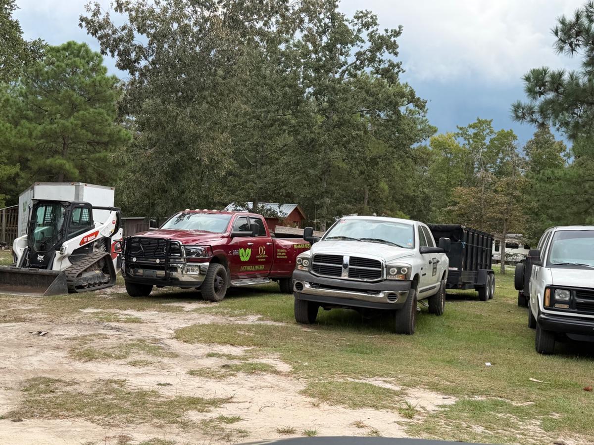 CG Landscaping Services trucks, dump trailer and skid steer staged for a tree job