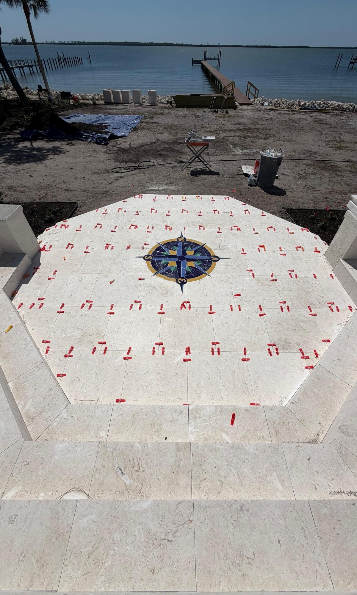 Travertine landing with a compass medallion being set by Christo & Pedroni Tile