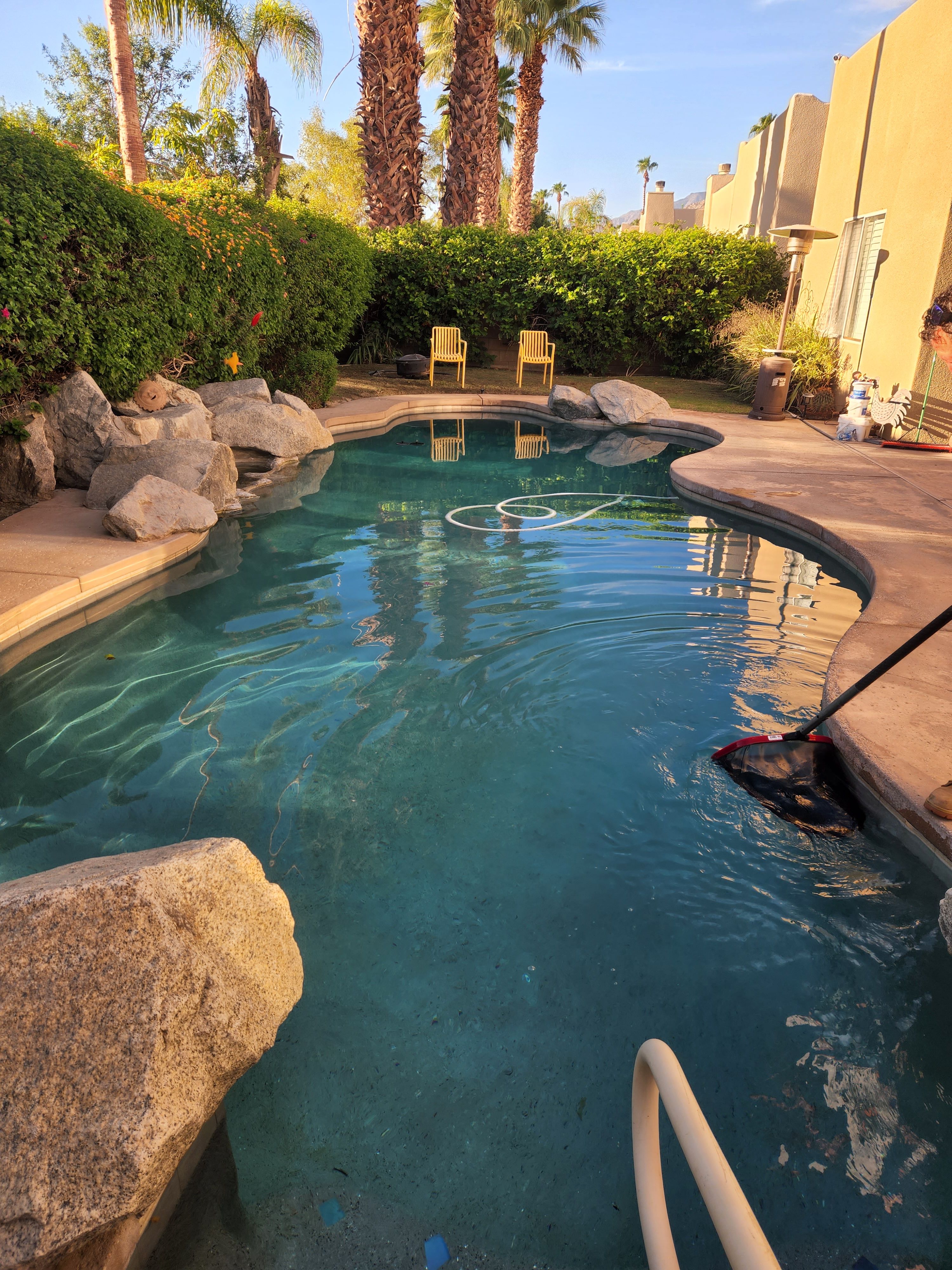 Pool brush and hose in a clean desert swimming pool serviced by Clear Waters Pool Service in the Coachella Valley