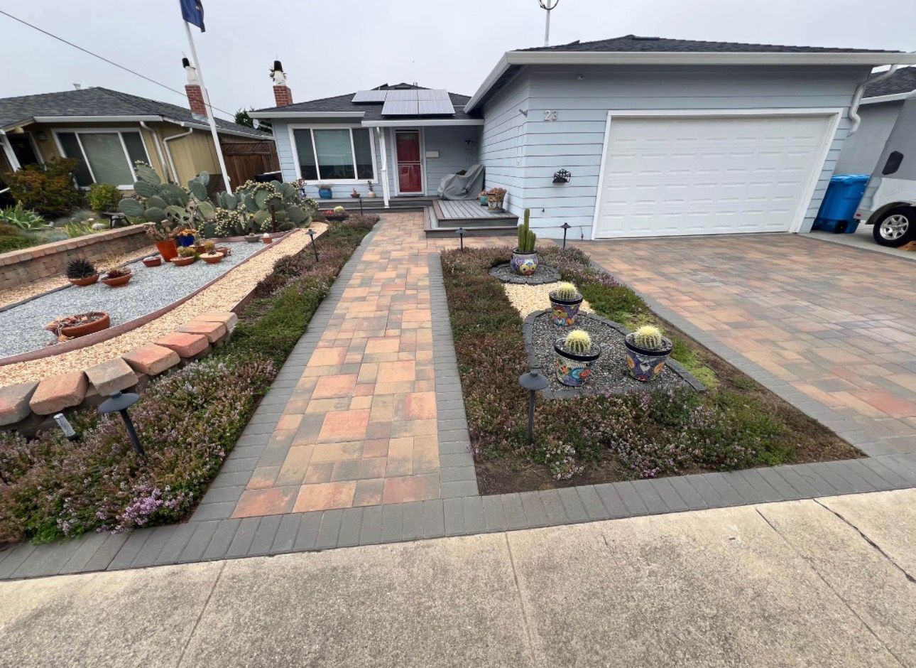 Paver driveway and walkway through a front-yard garden