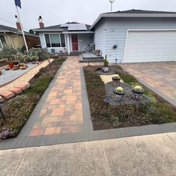 Paver driveway and walkway through a front-yard garden
