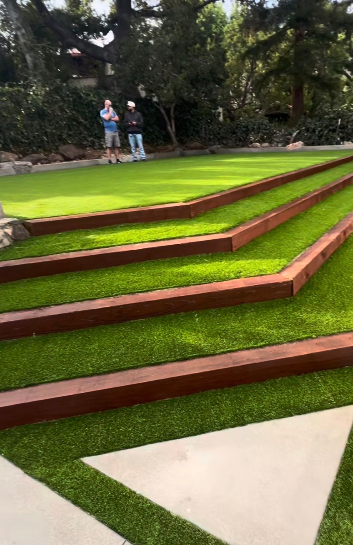 Terraced artificial turf with timber edging and concrete pads