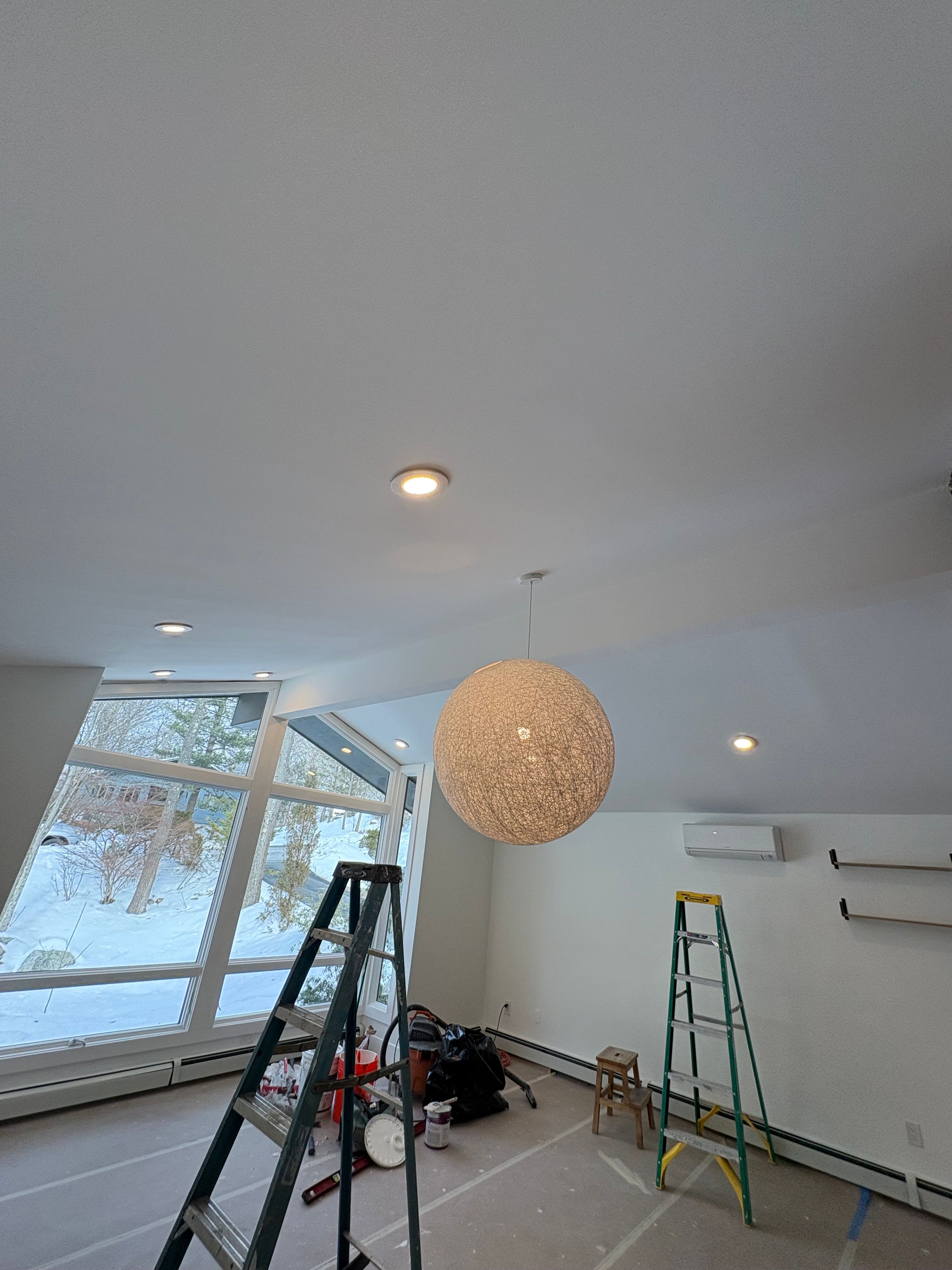 Vaulted room painted white, with floor-to-ceiling windows and ladders still in place — FE Pro Painting
