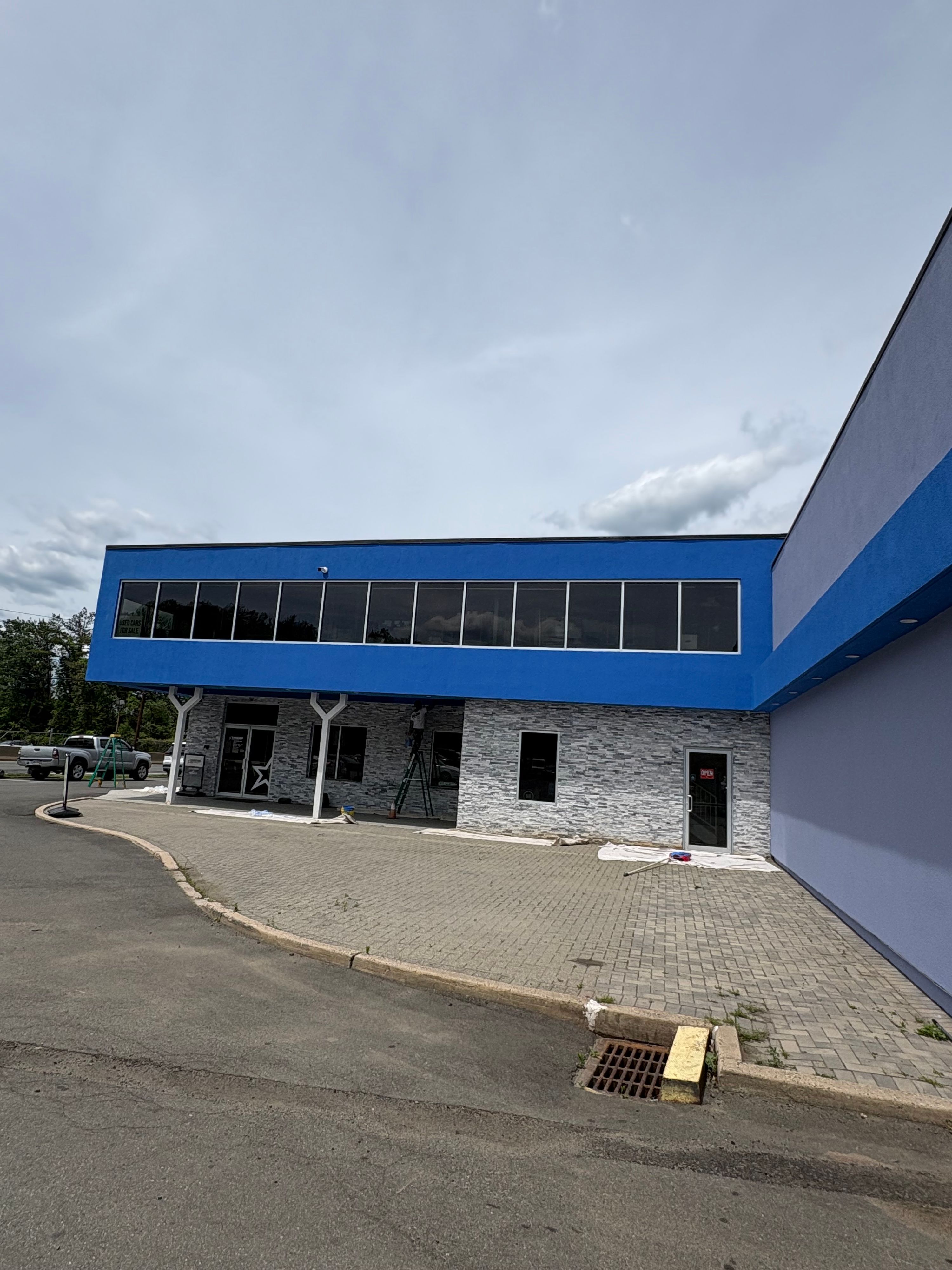 Commercial building exterior finished in blue and grey, with a stone-clad entrance — FE Pro Painting
