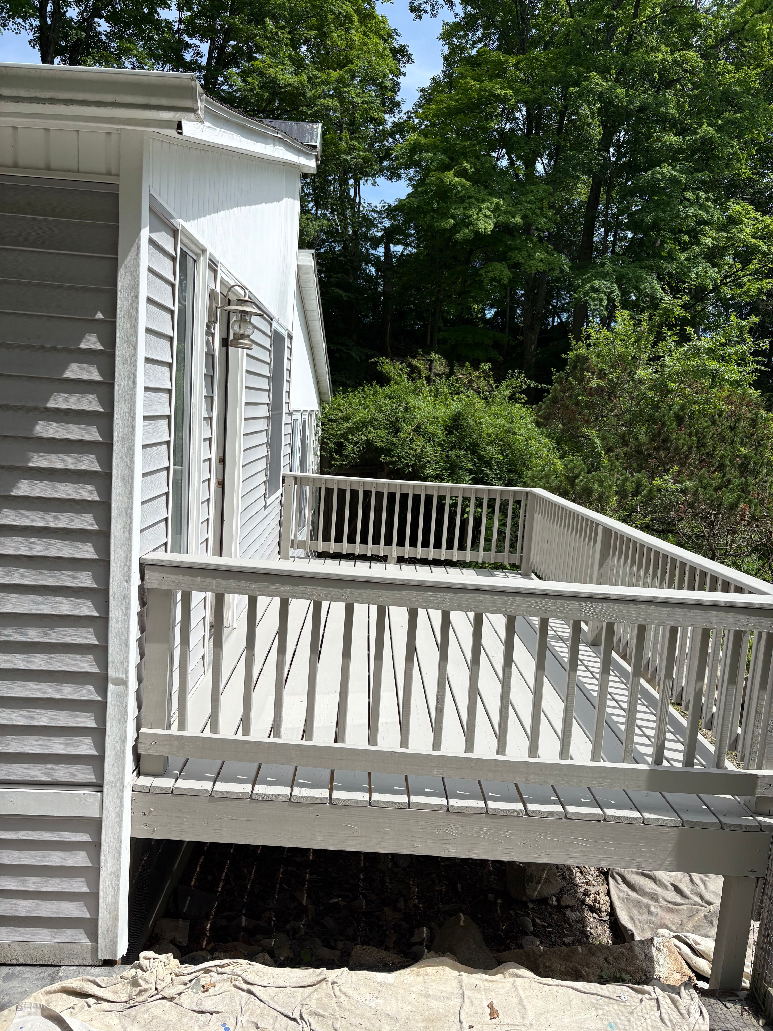 Second-storey deck with freshly painted white railings against pale siding — FE Pro Painting