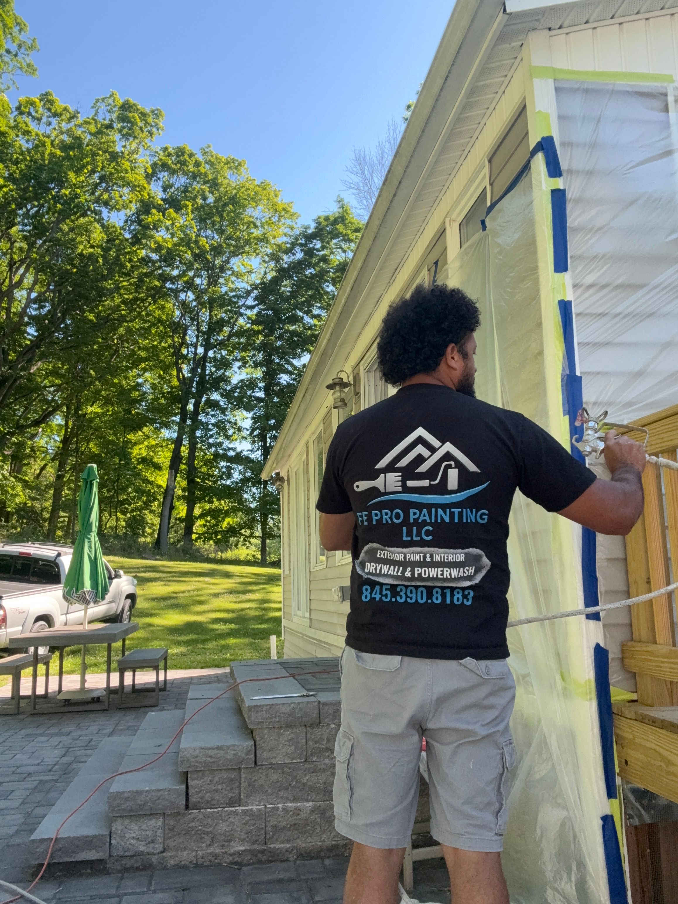 FE Pro Painting crew member cutting in around trim while painting a house exterior — FE Pro Painting