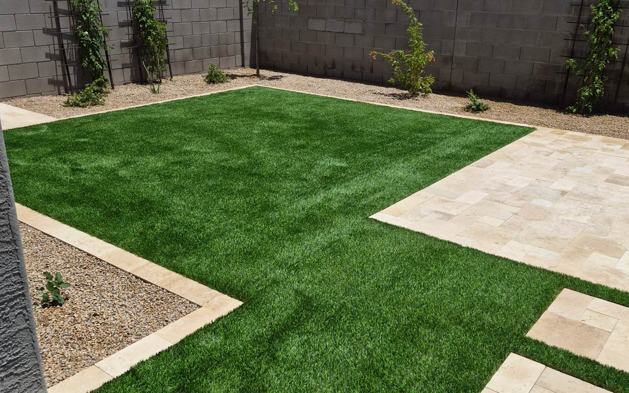 Finished Phoenix backyard by German LLC — travertine patio, synthetic grass and block wall