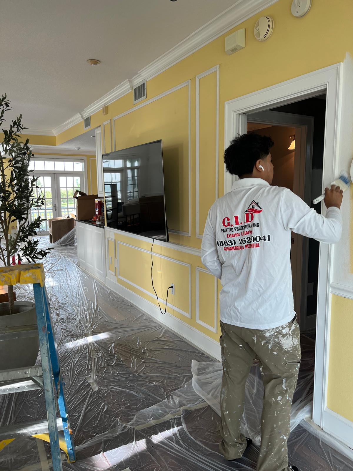 GLD Painting Professional painter cutting in trim on a yellow accent wall