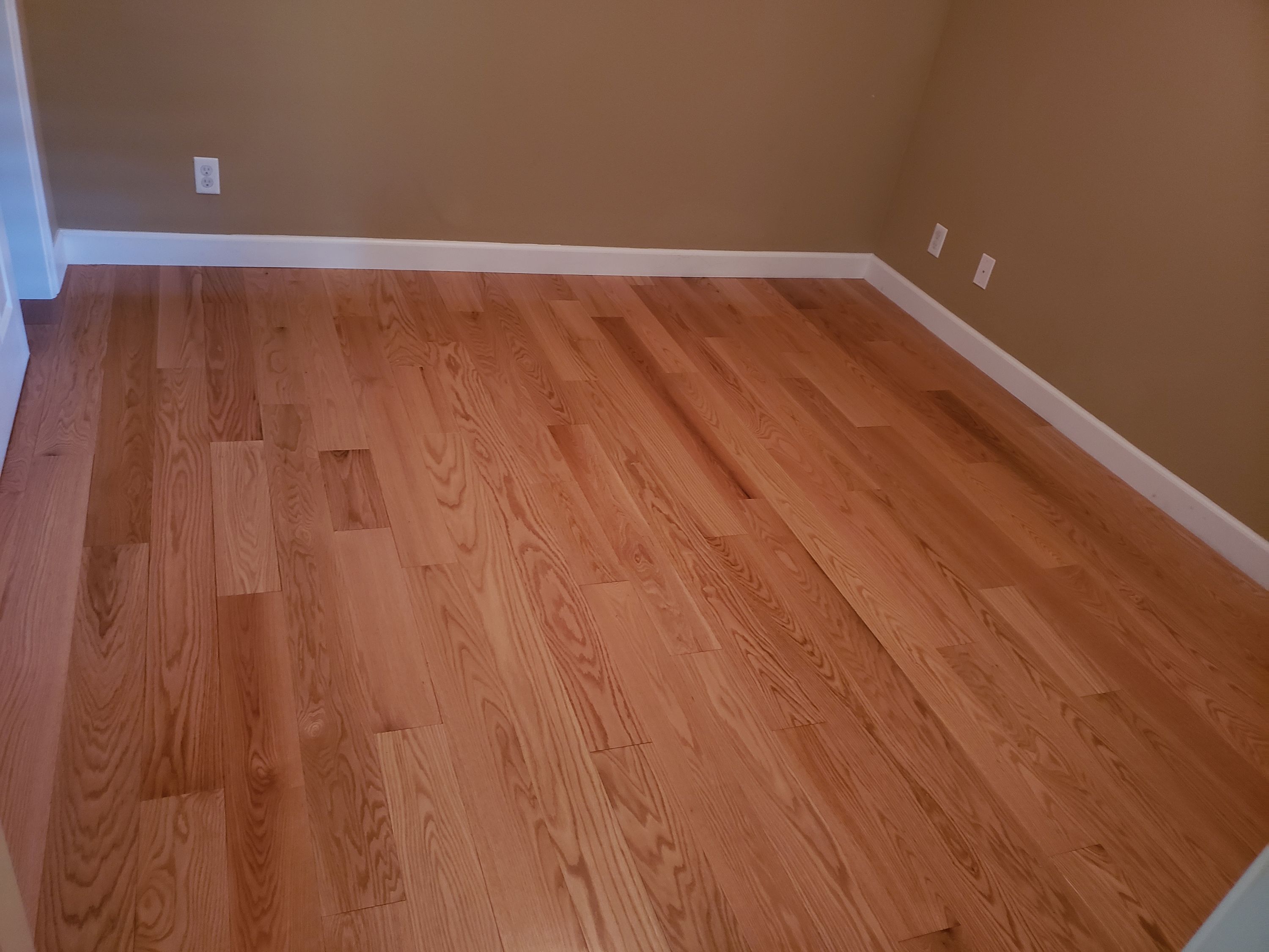 Red oak flooring finished with fresh white baseboard by Heavenly Floors, Inc.